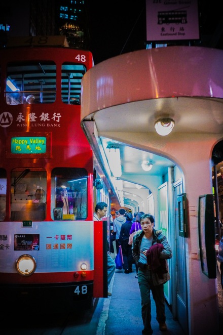 A pink bus stop, a red bus and blue lights in Hong Kong